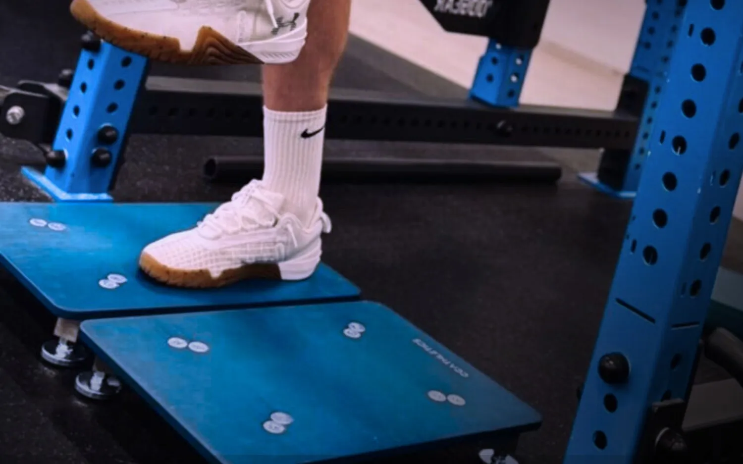 An athlete standing on a pair of PlateMate force plates in a squat rack